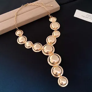 Close-up of minimalist gold metal necklace with shiny round disk pendants