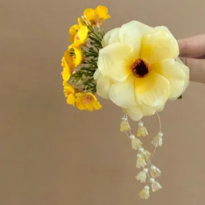 Macro detail of a bright yellow floral hair clip featuring elegant pearl tassel charms.