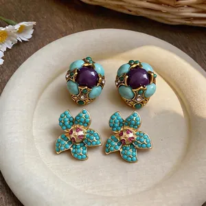 Orecchini a fiore vintage con perline turchesi e cristalli su un piatto decorativo