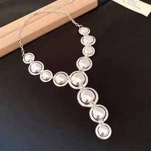 Detailed view of silver polished circular discs on a vintage style metal Y-shaped necklace.