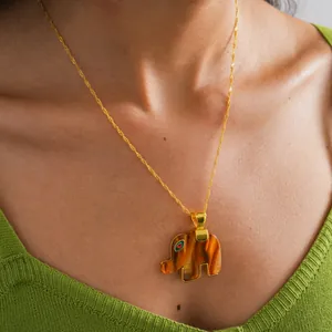 Detailed view of the resin elephant pendant necklace on a model's neckline