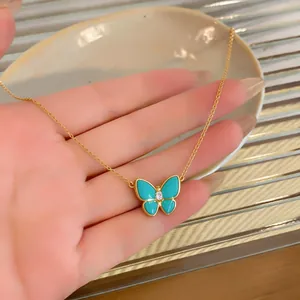 Detail view of a gold-plated butterfly pendant necklace with turquoise wings and zircon