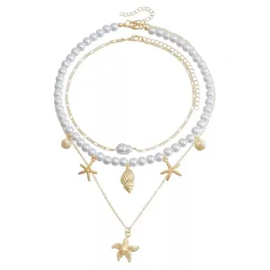 Detail view of gold starfish and conch charms on a multi-layer white pearl necklace set