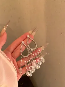 Close-up detail of silver-tone teardrop tassel earrings with sparkling zircons and pearls