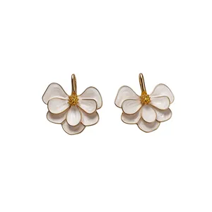 Elegant white enamel flower drop earrings with gold-toned edges and crystal centers.
