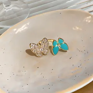 Detail view of an adjustable gold ring featuring sparkling zircon and blue resin butterflies.