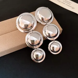 Detailed view of polished silver tiered circular dangle earrings on display.