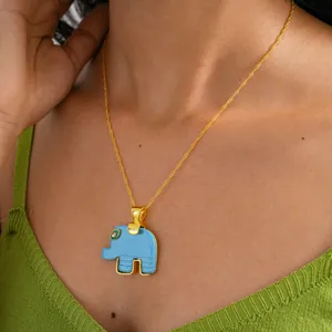 Detail view of a blue resin elephant pendant on a delicate gold chain for women
