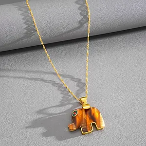 Detailed macro view of amber resin elephant pendant with sparkling eye on gold chain.