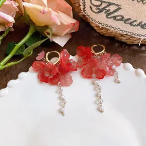 Elegant floral tassel earrings with faux pearls on a white decorative plate.