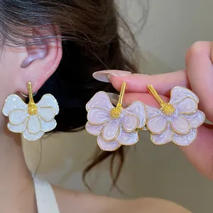 Macro detail of elegant flower stud earrings featuring white and purple enamel petals