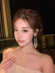 Close-up of French-style silver tassel earrings with sparkling zircon on a model