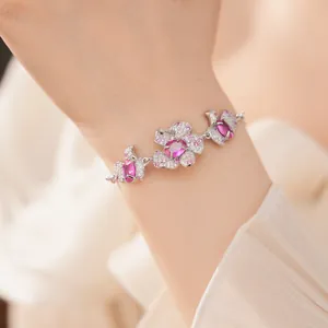 Elegantes silberfarbenes Armband mit zarten rosa Blumenanhängern und funkelnden Zirkonen.