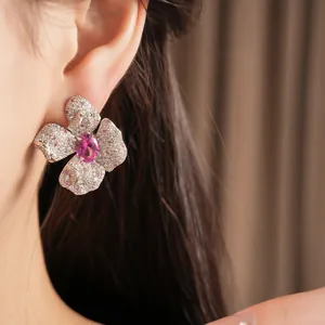 Detailansicht eines rosa Zirkonia-Blumenohrrings an einem Model.