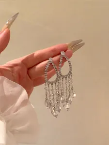 Detailed view of elegant silver teardrop tassel earrings featuring sparkling crystals.