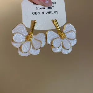 Detailed macro view of white enamel flower stud earrings with gold stamen