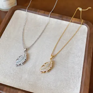 Close-up of elegant gold and silver feather necklaces featuring zircon and mother of pearl inlay.