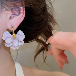 Close-up detail of a purple oil drip flower earring with gold-tone edges on a model's ear