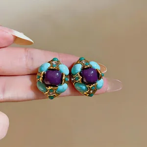 Dettaglio di orecchini a lobo vintage a fiore con pietre viola e turchesi