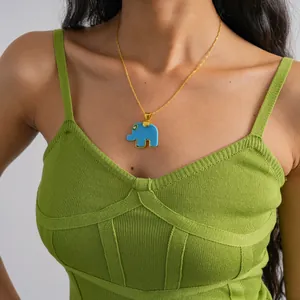 Detail of a minimalist gold chain necklace with blue resin elephant pendant on model