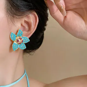 Primo piano di un elegante orecchino a fiore turchese con cristallo rosso centrale