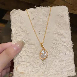 Close-up detail of luxury 18k gold-plated feather pendant necklace with mother-of-pearl inlay