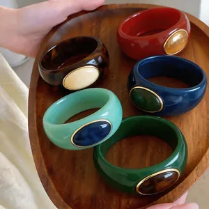 Macro detail of various colorful acrylic marbled bangles displayed on a wooden tray