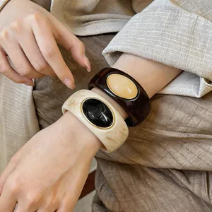 Detailed view of chunky acrylic marbled bangles worn on wrist showing retro design and finish
