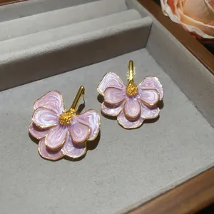 Detail view of elegant pink oil-dripped flower stud earrings in a jewelry tray.