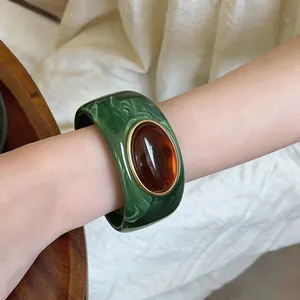 Close-up of a green marbled acrylic bangle featuring a large oval amber gemstone detail