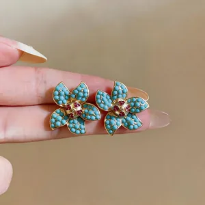 Dettaglio macro di orecchini a lobo a forma di fiore vintage con perline turchesi e strass