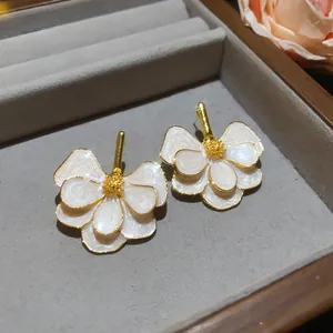 Macro view of elegant white enamel flower stud earrings with detailed golden edges.