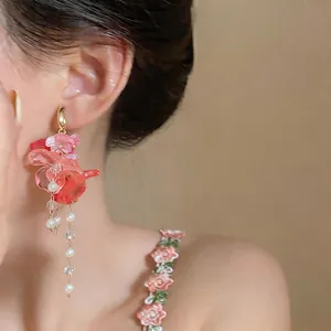 Detail shot of an elegant pink floral tassel earring with pearls worn on a model's ear
