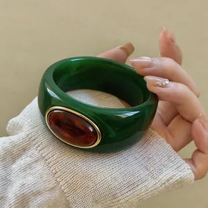 Close-up detail of a dark green acrylic blooming bangle with a central amber stone inlay