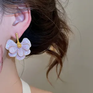 Close-up of elegant purple enamel flower stud earrings with gold trim worn on ear.