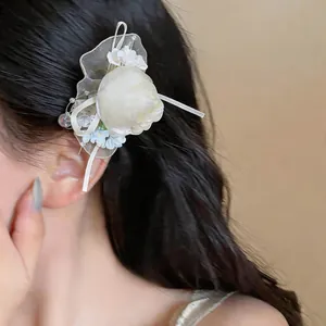 Close-up of elegant chiffon flower hair clip with lace detail worn on wavy dark hair.