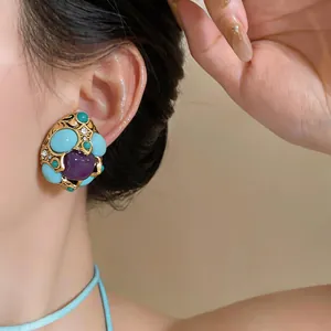 Primo piano di orecchini vintage con pietre turchesi e viola sull'orecchio di una modella