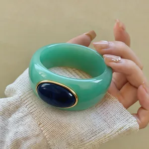 Macro view of green acrylic bangle with a deep blue marbled inset stone