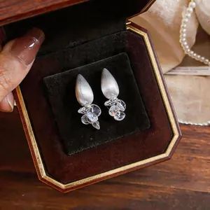 Close-up of French style matte silver water-drop stud earrings with zircon crystals
