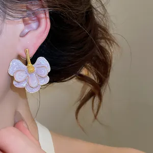 Close-up detail of elegant purple drip oil floral earrings with gold accents worn on an ear