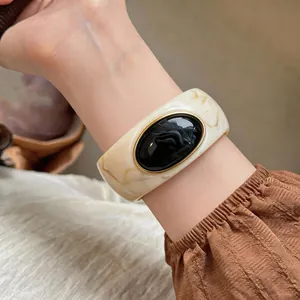 Close-up of the elegant marble-textured acrylic bangle with a black oval inset and gold trim
