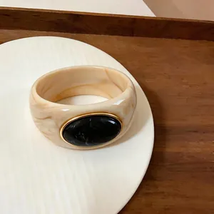 Acrylic marble bangle with a large black stone and gold metal frame detailing