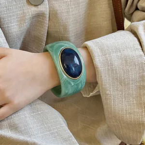 Chunky green acrylic marble bangle with large blue stone detail worn on wrist