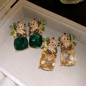 Detail view of panda earrings featuring large square emerald and champagne crystals