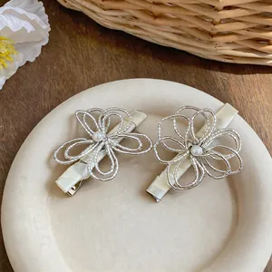 Dettaglio di eleganti fermagli per capelli a forma di fiore d'argento con perla.