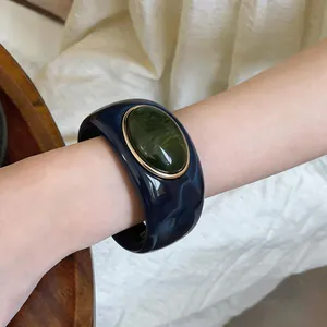 Detailed close-up of a marbled acrylic bangle with a green resin stone on a model's arm