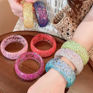 Macro view of colorful summer resin bangles with shimmering foil details on a model's wrist