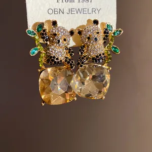Close-up of panda stud earrings with large square champagne crystals and leafy accents