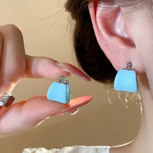 Élégantes boucles d'oreilles en émail bleu clair en forme de U sur l'oreille du modèle