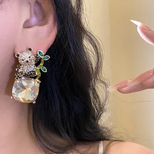 Close-up of sparkling panda stud earring with a large square faceted crystal pendant.